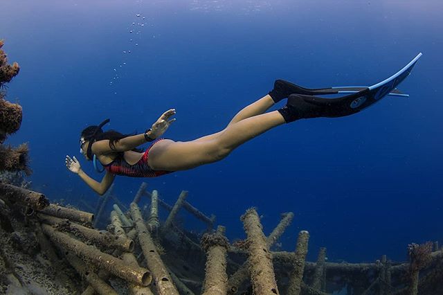 Nikita Fima sedang freediving dengan long finn & one-piece swimwear